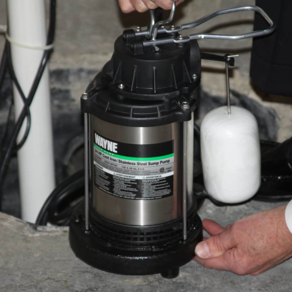 Man Holding Sump Pump Over Pit